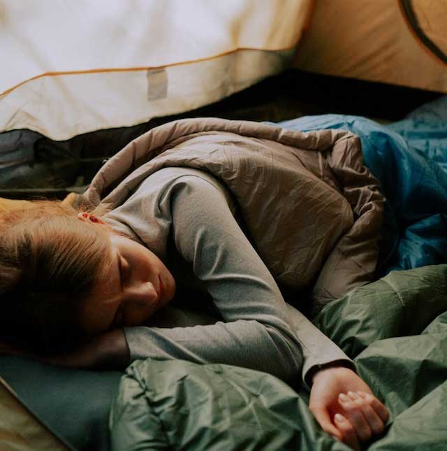 Girl sleeping in a sleeping Bag in a tent
